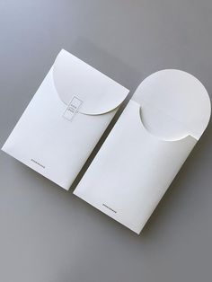 two white envelopes with one open and the other closed, on a gray surface