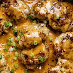 chicken covered in gravy with green onions and cheese on top, sitting in a skillet