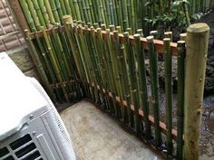 an air conditioner sitting next to a bamboo fence