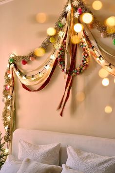 a christmas tree hanging from the side of a wall next to a bed with white pillows