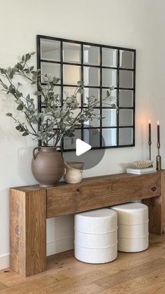 a wooden table topped with vases filled with flowers and candles next to a mirror