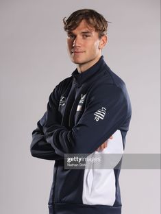 a man with his arms crossed, wearing a blue and white track suit stock photo