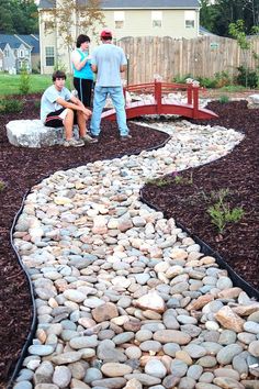 two people are sitting on a bench in the middle of a garden with rocks and gravel