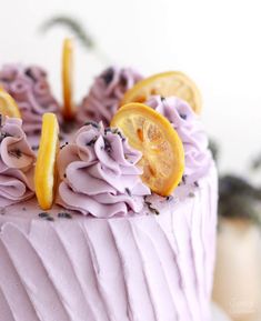 there is a cake with purple frosting and lemon slices on the top, along with lavender icing