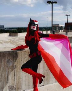 a woman dressed in catwoman costume posing for the camera with her red and white umbrella