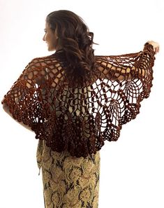 a woman wearing a crochet shawl and patterned pants with her back to the camera