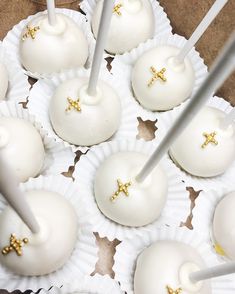 white cake pops with gold crosses on them are ready to be cut and served for guests