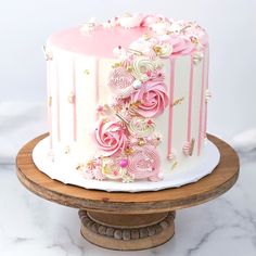 a pink and white cake on a wooden stand