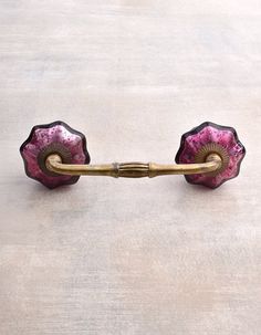 a pink and black flower shaped glass door handle on a white surface with gold accents