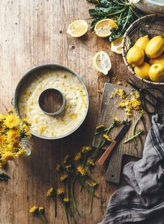 a bowl of oatmeal next to some flowers and lemons on a wooden table