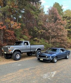 two trucks parked next to each other on the side of a road in front of trees