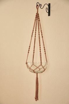 a hanging glass bowl on a wall with beaded cord and metal hook, attached to the wall