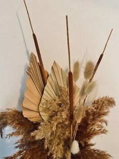 an arrangement of dried flowers and feathers in a vase