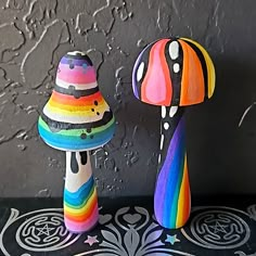 two colorful mushrooms are sitting next to each other on a table with black and white designs