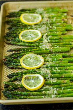 asparagus spears with lemons and parmesan on a baking sheet, ready to be cooked