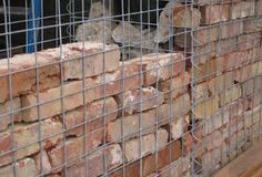 a pile of bricks sitting on top of a wooden floor next to a metal fence