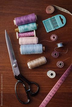 several spools of thread, scissors and measuring tape on a table with sewing supplies