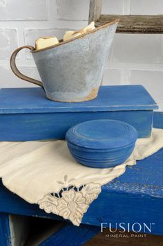 a blue table topped with a metal cup and bowl