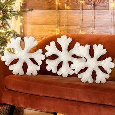 two snowflakes sitting on top of a couch next to a christmas tree