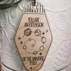 a wooden ornament with an image of the planets and stars on it that says, you are an extension of the universe itself