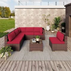 a red couch sitting on top of a wooden floor next to a table and potted plant