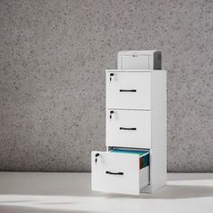 three file cabinets stacked on top of each other in front of a wall with grey speckles