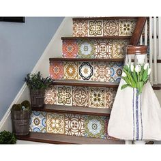 some flowers are sitting on the steps in front of a wall with decorative tile designs