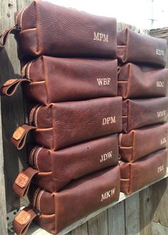 a stack of brown leather bags sitting on top of a wooden fence