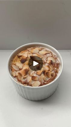 a bowl filled with food sitting on top of a white counter next to a cup