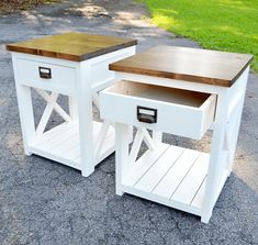 two white side tables sitting on top of a gravel road