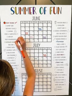 a young child writing on a summer of fun calendar