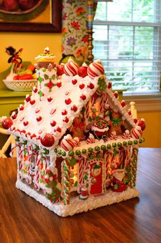 a gingerbread house decorated with candy canes and candies on the roof is sitting on a table in front of a window