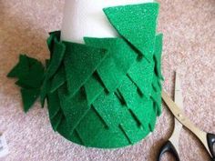 a pair of scissors sitting on top of a table next to a green cup with leaves