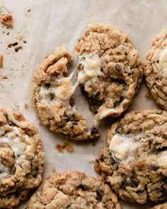 chocolate chip cookies with white icing and crumbled on top are sitting on a piece of parchment paper