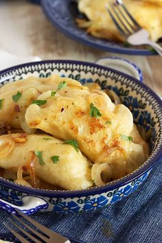 a bowl filled with dumplings on top of a blue and white plate next to a fork