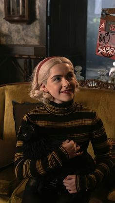 a woman sitting on top of a couch in a living room next to a clock