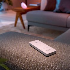 a remote control sitting on top of a couch in a living room next to a coffee table