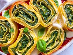 an assortment of food items displayed on a white plate with red sauce and green leaves