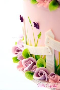 a pink cake decorated with flowers and a white fence