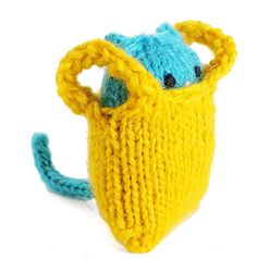 a knitted yellow bag with a blue nose and mouth sitting on top of it