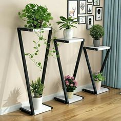 three black and white plant stands with plants on them