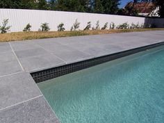 an empty swimming pool surrounded by grass and trees