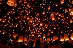 many people are flying lanterns in the air