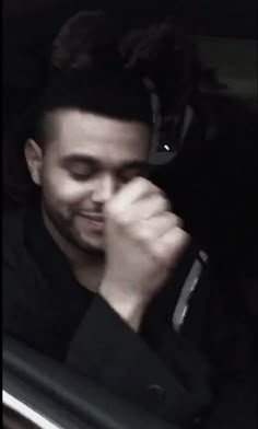 a man sitting in the back seat of a car talking on a cell phone