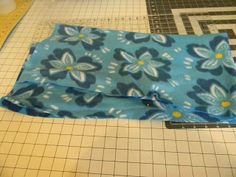 a blue and white flowered cloth laying on top of a cutting board next to a ruler