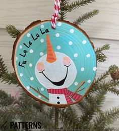 a christmas ornament with a snowman on it hanging from a pine tree