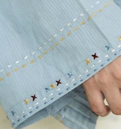 a close up of a person's hand holding something in their left hand and wearing a blue shirt with stars on it