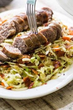 a plate with meat and coleslaw on it is being eaten by a fork