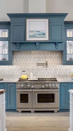 a kitchen with blue cabinets and stainless steel stove top oven, white counter tops and wooden flooring