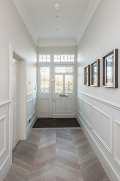 an empty hallway with two framed pictures on the wall and another door in the background